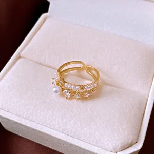 Vintage double-layered gold ring with pearls and sparkling cubic zirconia in jewelry box.