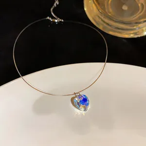 Close-up of a heart-shaped iridescent crystal pendant on an invisible choker necklace.