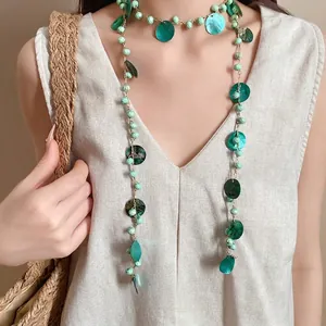Collana boho stile etnico con perline verdi e nappe di conchiglia indossata da modella