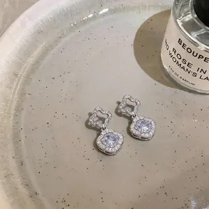 Close-up of elegant flower-shaped silver zircon drop earrings displayed on a ceramic tray