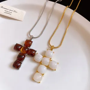 Macro detail of brown and white resin cross pendants on gold and silver snake chains