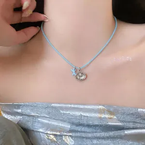 Primer plano de collar de cuentas azules con lazo y dijes de conchas en la modelo.