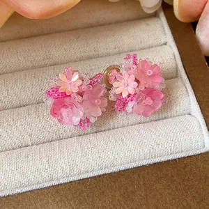 Gros plan de boucles d'oreilles fleurs en perles de verre roses dans un plateau beige