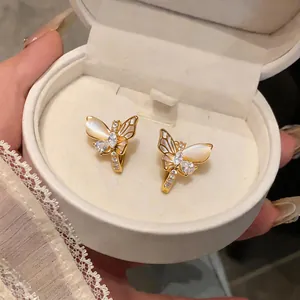 Vue détaillée d'exquises boucles d'oreilles papillon dorées avec zircons et pierres