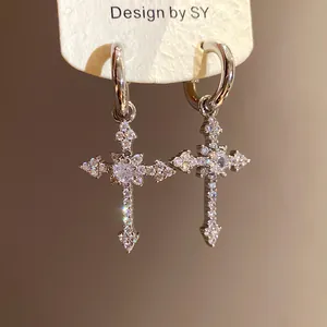 Close-up of elegant silver cross dangle earrings with sparkling zircon stones