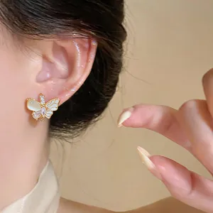 Gros plan détaillé d'une boucle d'oreille papillon élégante avec œil de chat et zircon.