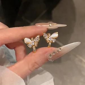 Détail de boucles d'oreilles papillon en or élégantes avec zircons et ailes en œil de chat.