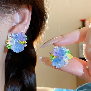 Vue détaillée de boucles d'oreilles fleurs en perles de verre colorées portées à l'oreille