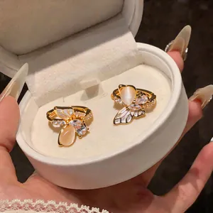 Détail de boucles d'oreilles papillon dorées avec pierres œil de chat et zircons