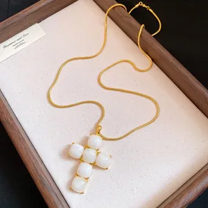 Close-up of a resin cross pendant necklace with a gold-tone snake chain on a display board