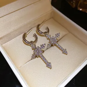 Close-up of elegant silver-tone hoop earrings featuring sparkling zircon cross charms
