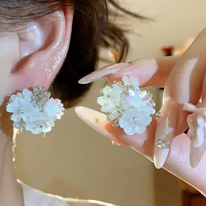 Gros plan de boucles d'oreilles fleurs en perles blanches faites à la main élégantes.