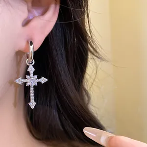 Close-up of sparkling zircon cross pendant earring on ear for fashion look