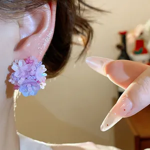 Vue détaillée d'élégantes boucles d'oreilles fleurs en perles violettes portées à l'oreille.