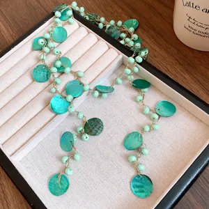 Dettaglio della collana boho con perle in acrilico e conchiglie verdi nel vassoio