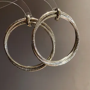 Detailed close-up of shimmering silver textured hoop earrings with a retro finish