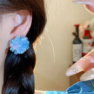 Détail de boucles d'oreilles fleur en perles bleues montrant un travail délicat