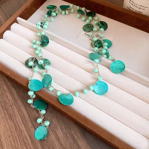 Primo piano di una collana etnica bohémien con perline acriliche e dischi di conchiglia.