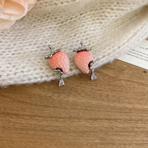 Detailaufnahme von rosa Erdbeer-Ohrsteckern aus Harz mit funkelnden Kristall-Tropfen.
