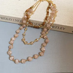 Detail view of a layered bohemian crystal necklace with amber beads on a vintage book