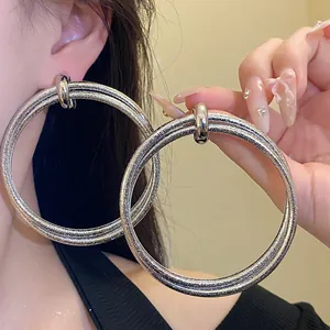 Close-up of large silver-tone hoop earrings featuring a unique crinkled glitter texture