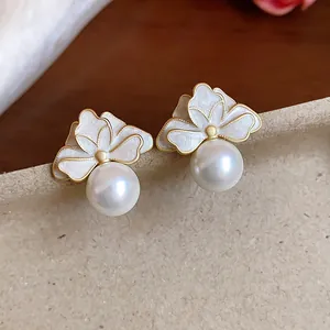 Detailed shot of elegant French style flower stud earrings with white enamel and hanging pearl