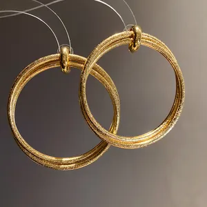 Detailed macro view of vintage gold-plated hoop earrings with unique metallic texture.