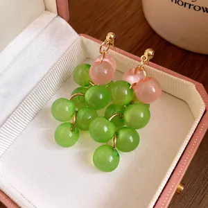 Detail view of colorful resin beaded grape cluster dangle earrings in pink jewelry box