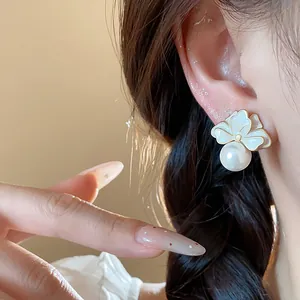 Close-up detail of French style enamel flower and pearl stud earring worn by a model