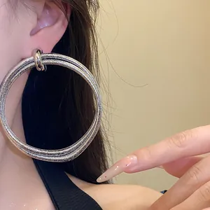 Close-up detail of large vintage style silver textured multi-layered hoop earrings worn by model