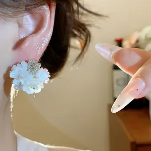 Gros plan de boucles d'oreilles fleurs en perles de verre blanches avec paillettes