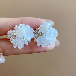 Détail rapproché de boucles d'oreilles fleurs en perles blanches irisées
