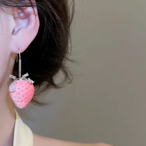 Nahaufnahme eines süßen rosa Harz-Erdbeere-Ohrrings mit glitzernden Zirkonia am Ohr
