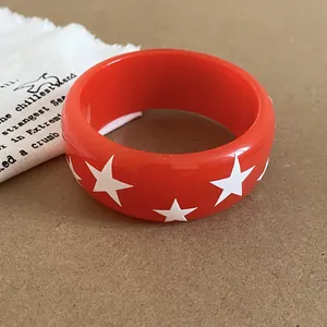 Vue macro d'un bracelet en résine rouge avec motif d'étoiles blanches et finition brillante