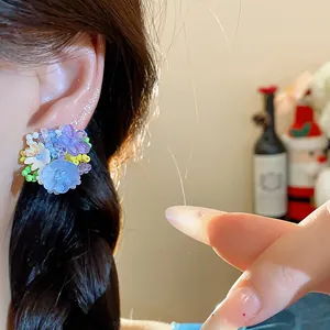 Vue détaillée de boucles d'oreilles fleurs en perles de verre colorées portées à l'oreille.