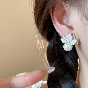 Detailed macro shot of elegant French style flower and pearl stud earring on model's ear