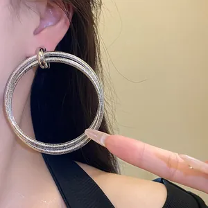 Detailed close-up view of oversized sparkling silver hoop earrings worn on an Asian model