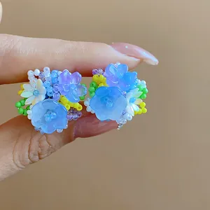 Gros plan détaillé de boucles d'oreilles fleurs en perles de verre colorées et bleues.