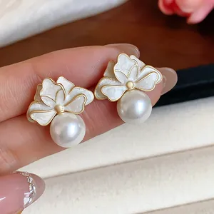 Close-up detail of French style enamel flower stud earrings with elegant white pearls