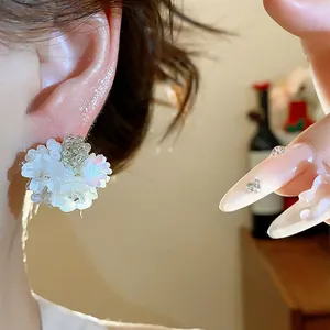 Détail rapproché de boucles d'oreilles fleurs en perles blanches portées par un mannequin