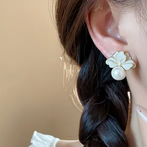 Elegant flower pearl stud earring closeup shown on female model's ear