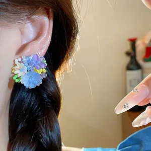Gros plan d'une boucle d'oreille fleurie en perles de verre colorées portée à l'oreille.
