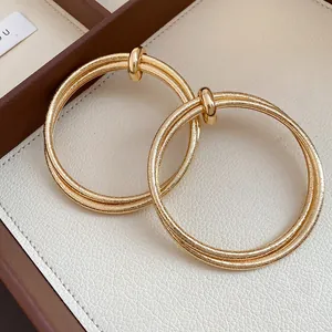 Close-up of gold metal hoop earrings with wrinkled texture and double-ring design