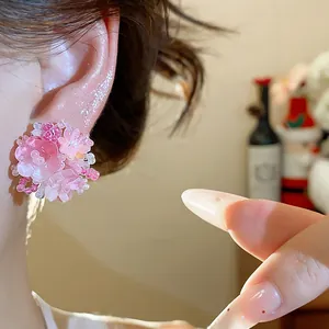 Détail des élégantes boucles d'oreilles fleur en perles roses sur un lobe d'oreille