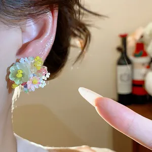Vue rapprochée de délicates boucles d'oreilles fleurs en perles de verre sur une oreille