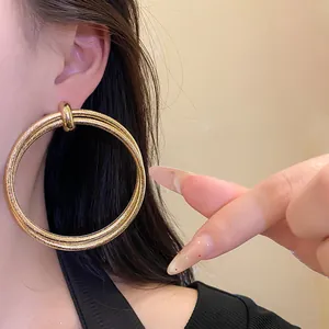 Close-up of large vintage gold textured double-hoop earrings worn by a model.