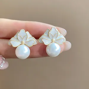 Detail view of French style flower earrings with white pearls and gold-tone enamel.