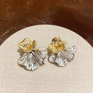Close-up view of gold and silver two-tone flower stud earrings with a sparkling center diamond