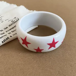 Détail d'un bracelet jonc en résine blanche avec des étoiles roses