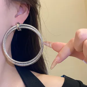 Detailed view of large silver double hoop earrings with metallic textured finish on ear